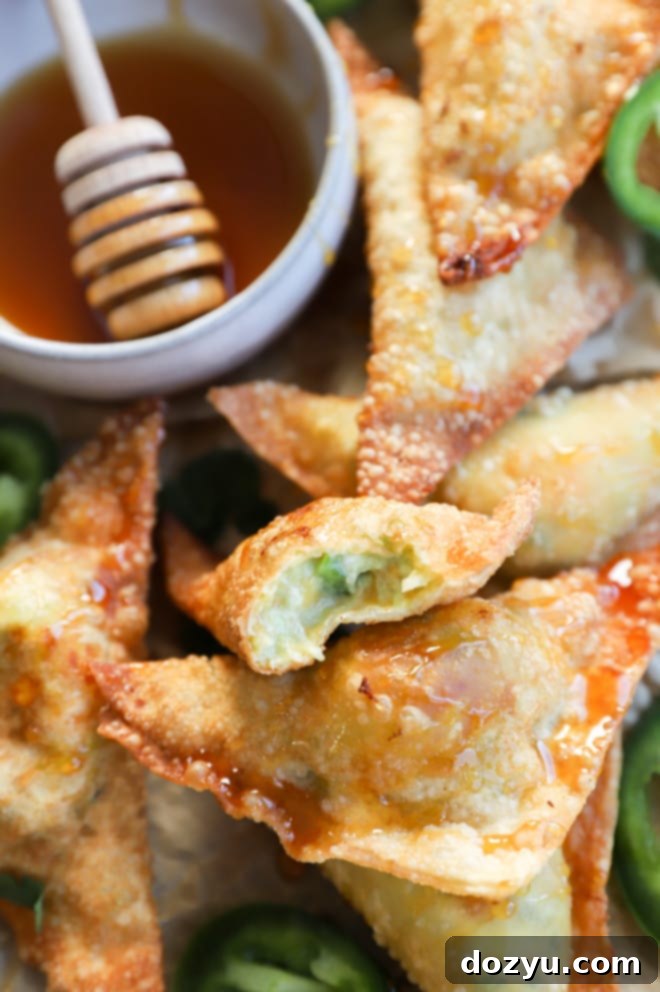 Avocado Jalapeño Popper Wonton Bites 11 A generous pile of golden-brown jalapeño popper avocado wontons arranged on a white platter, ready to be served