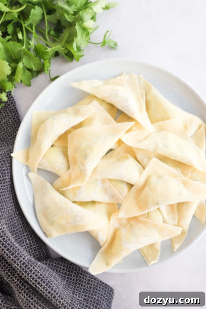 Avocado Jalapeño Popper Wonton Bites 4 Photo of uncooked jalapeño popper cream cheese wontons neatly arranged on a tray, ready for frying