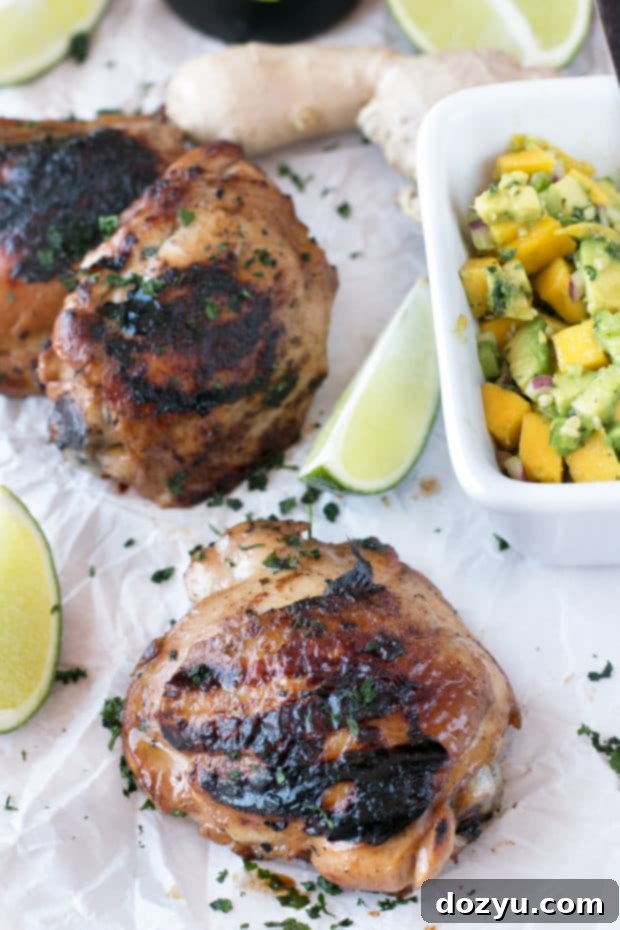 Zesty Ginger-Grilled Chicken Thighs with Creamy Avocado Salsa 3 Close-up shot of grilled chicken thighs marinated in spicy ginger, served with a chunky mango avocado salsa. A perfect, easy-to-make summer meal.