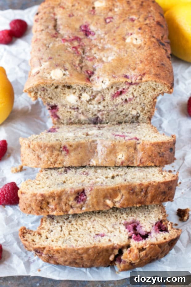 A large slice of Raspberry Lemon White Chocolate Chip Loaf on a plate, ready to be eaten.