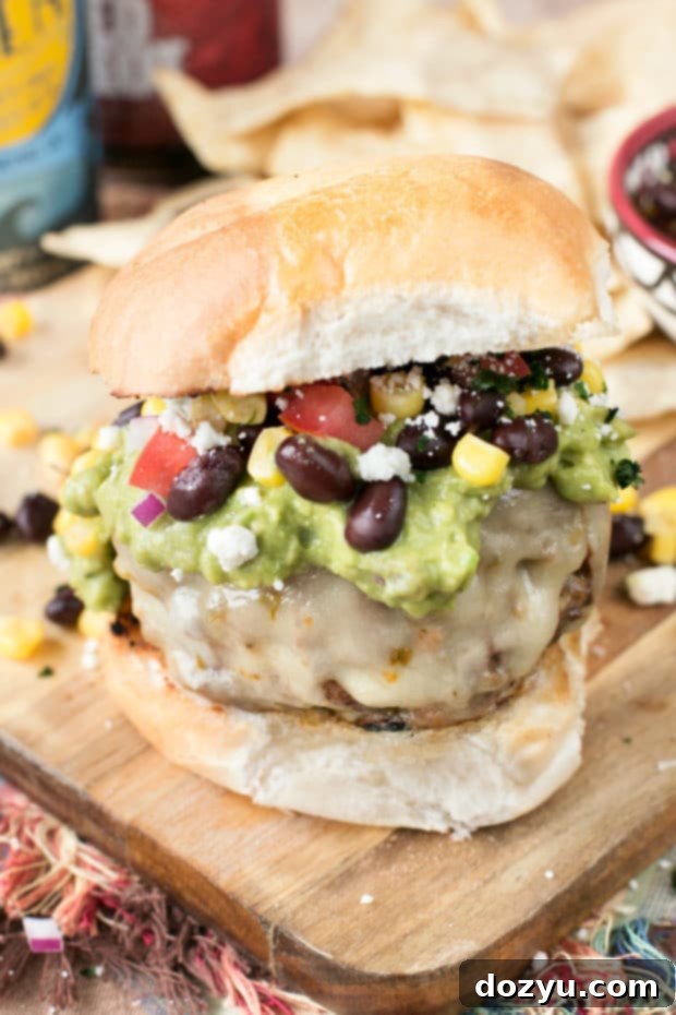 Juicy Southwestern Guacamole Burger on a sesame bun, topped with fresh guacamole, corn, and black beans, ready for a delicious meal.