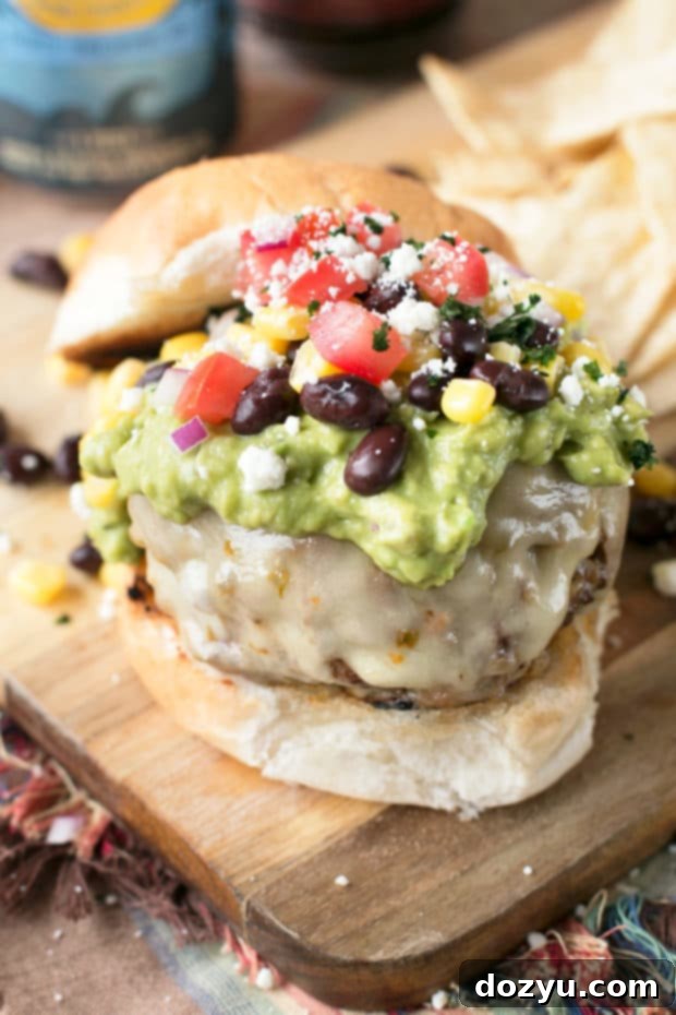 Close-up of a perfectly constructed Southwestern Guacamole Burger showing the creamy green guacamole, melted pepper jack cheese, and savory grilled patty.