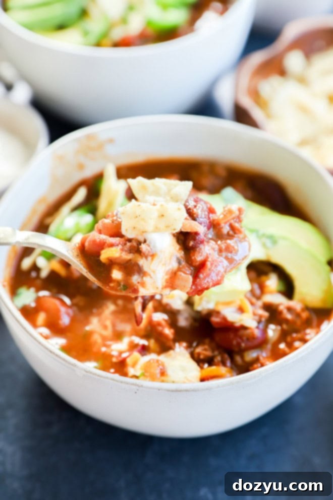 Spoons loaded with spicy taco chili and a variety of delicious toppings, ready for tasting.