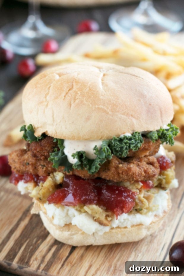 A beautifully layered Fried Turkey Thanksgiving Leftover Sandwich, showcasing crispy turkey, mashed potatoes, stuffing, and cranberry sauce on a toasted bun, drizzled with cajun gravy aioli.