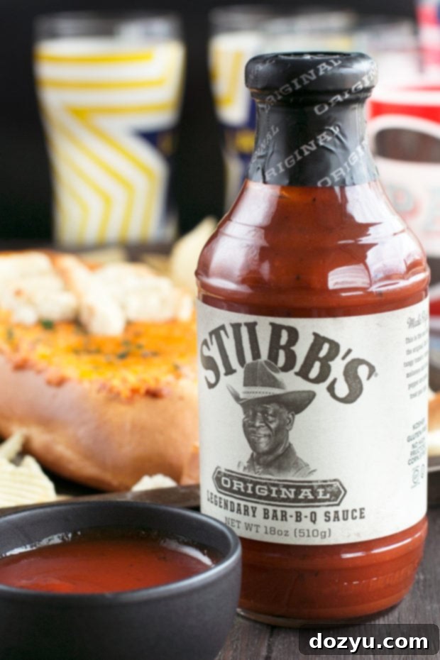 A vibrant, delicious football-shaped Cheesy Pulled Pork BBQ Bread Dip ready for a game day party.