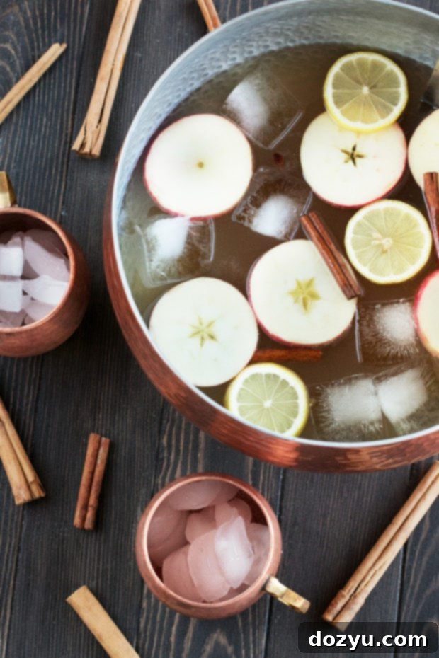 Gingerbread Bourbon Punch ready to serve in a large copper punch bowl, garnished with apple and cinnamon.