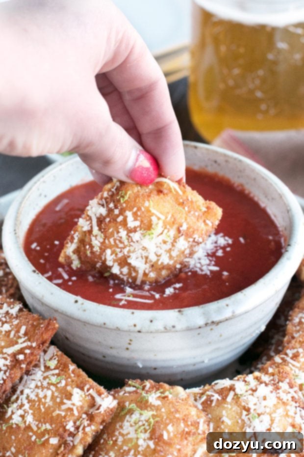 A close-up of a single Berbere Fried Ravioli, perfectly golden and dusted with lime zest and Parmesan cheese