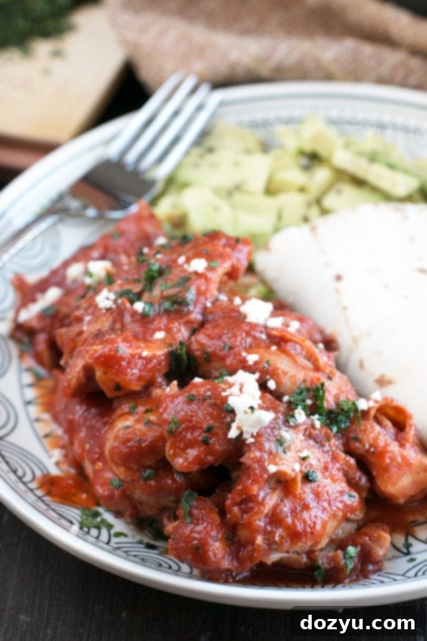 A portion of Chipotle Braised Chicken Thighs served with fresh avocado and tortillas.