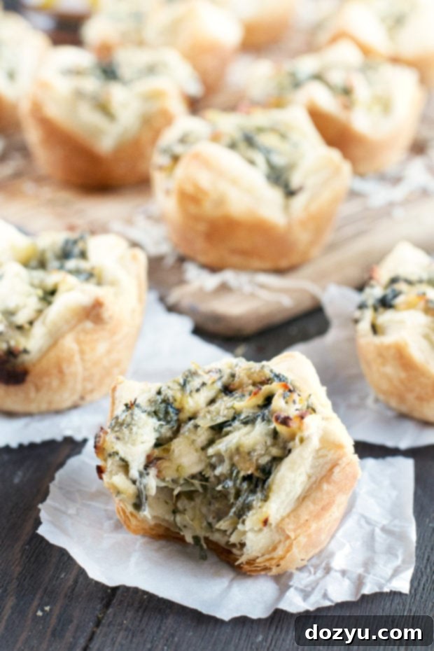 A tray of freshly baked Chicken Spinach Artichoke Dip Puffs, garnished with fresh parsley.