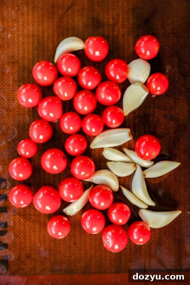 tomatos and garlic cloves on lined baking sheet before roasting