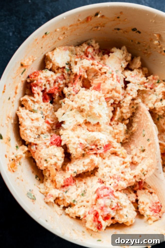 four cheese mixture with tomatoes and garlic in bowl with wooden spoon