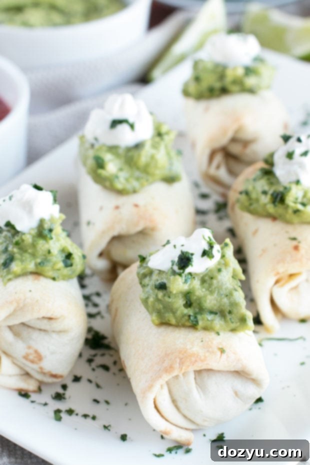 Stacked Baked Mini Chimichangas with a bowl of Creamy Spicy Guacamole in the background