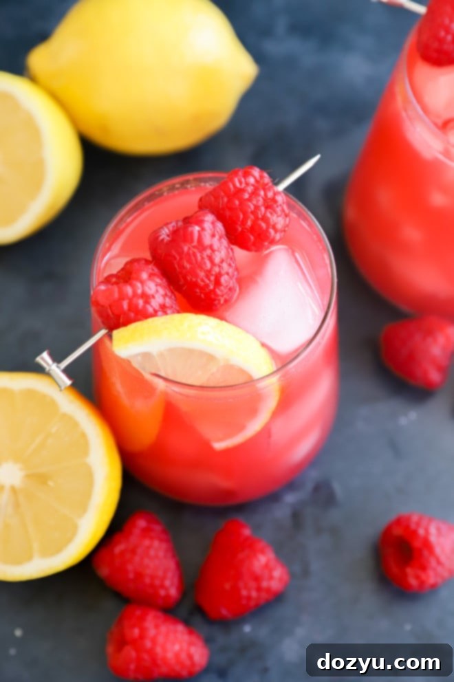 Vibrant Raspberry Vodka Lemonade served in elegant glasses, garnished with fresh raspberries and lemon slices, perfect for summer refreshment.