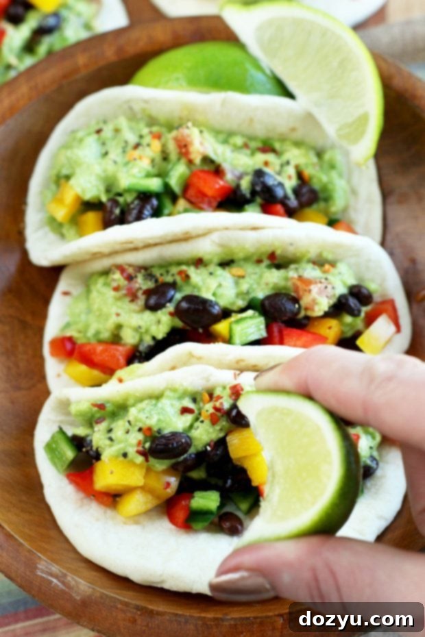 A spread of guacamole tacos garnished with cilantro and red pepper flakes