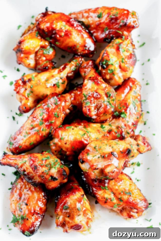 Platter of golden brown grilled beer marinated chicken wings garnished with fresh herbs, ready to be served at a summer BBQ.