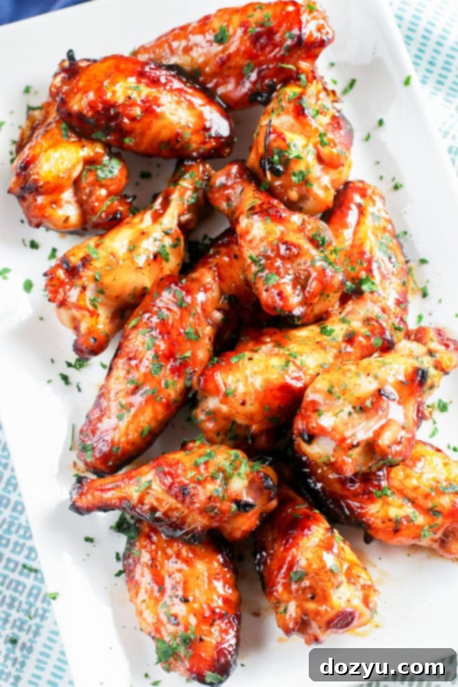 A beautiful platter of grilled chicken wings, garnished with fresh herbs and served with a side of BBQ sauce.