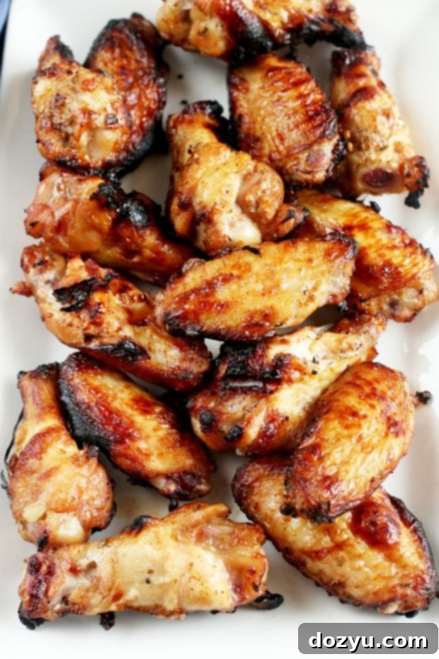 Perfectly golden and crispy Grilled Beer Marinated Chicken Wings, glistening with BBQ sauce.