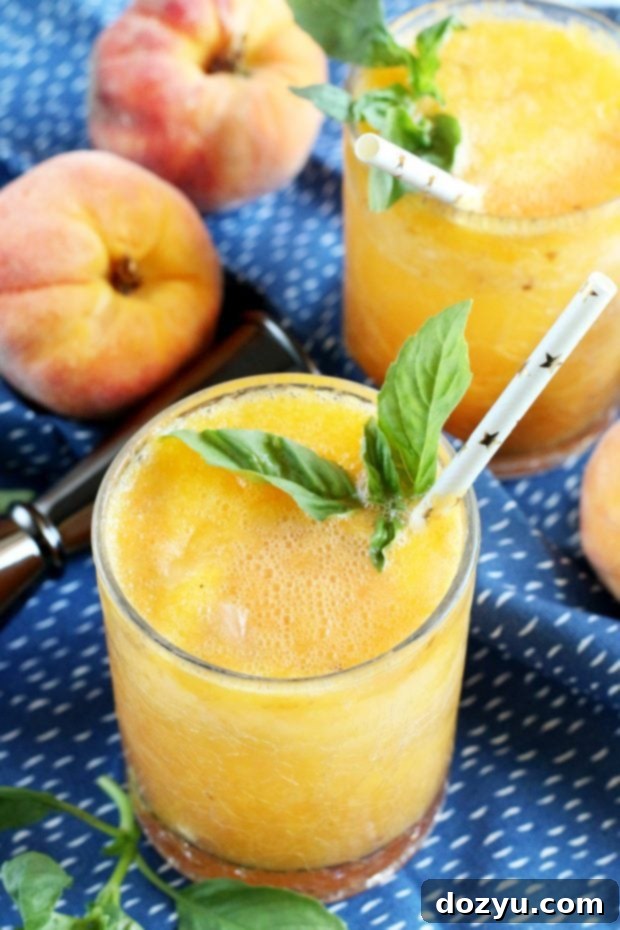 Caramelized Peach Gin Fizz 2 Roasted Peach Gin Fizz cocktail with fresh basil garnish on a wooden surface