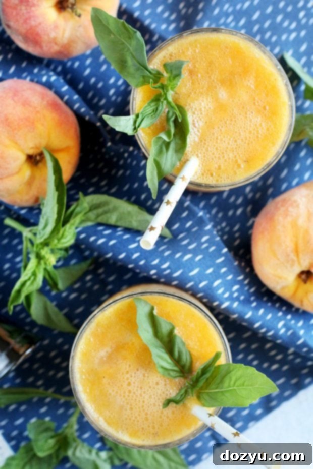 Caramelized Peach Gin Fizz 3 Two glasses of Roasted Peach Gin Fizz on a tray with fresh peaches and basil