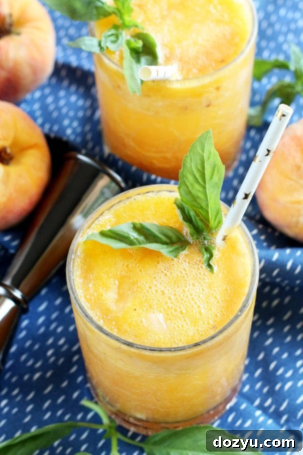 Caramelized Peach Gin Fizz 7 A high-angle shot of a Roasted Peach Gin Fizz cocktail with fresh peaches and basil