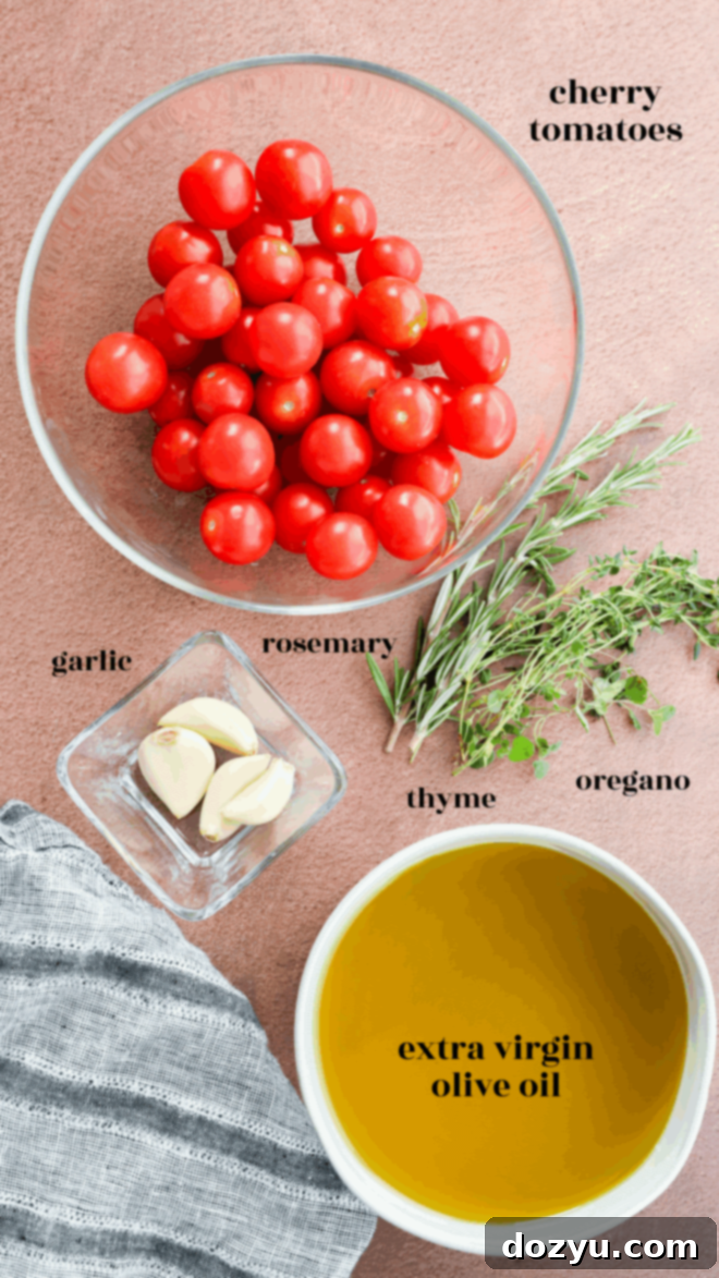 A bowl of cherry tomatoes, perfect for making cherry tomato confit, sits with extra virgin olive oil, garlic cloves, and sprigs of rosemary, thyme, and oregano on a pink surface next to a gray striped cloth. Ingredients are clearly labeled.