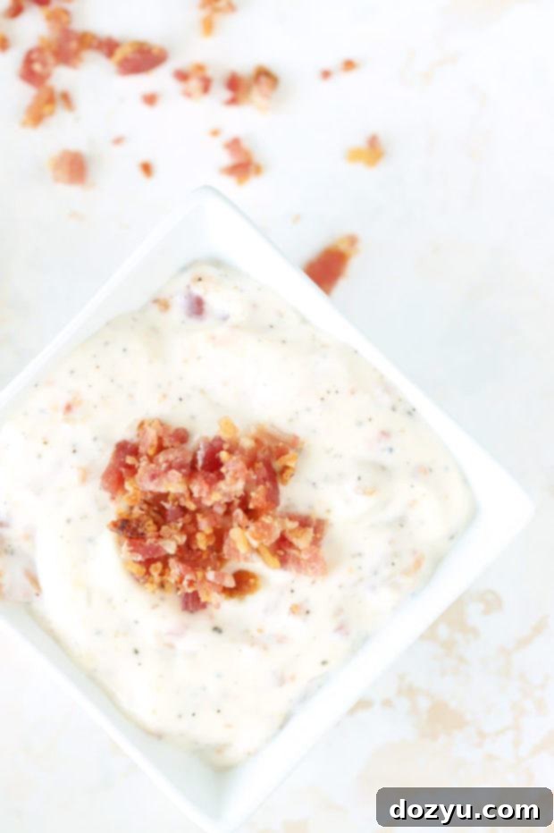 Smoky Bacon Aioli 2 Overhead image of bacon sauce in a small white bowl, garnished with herbs.