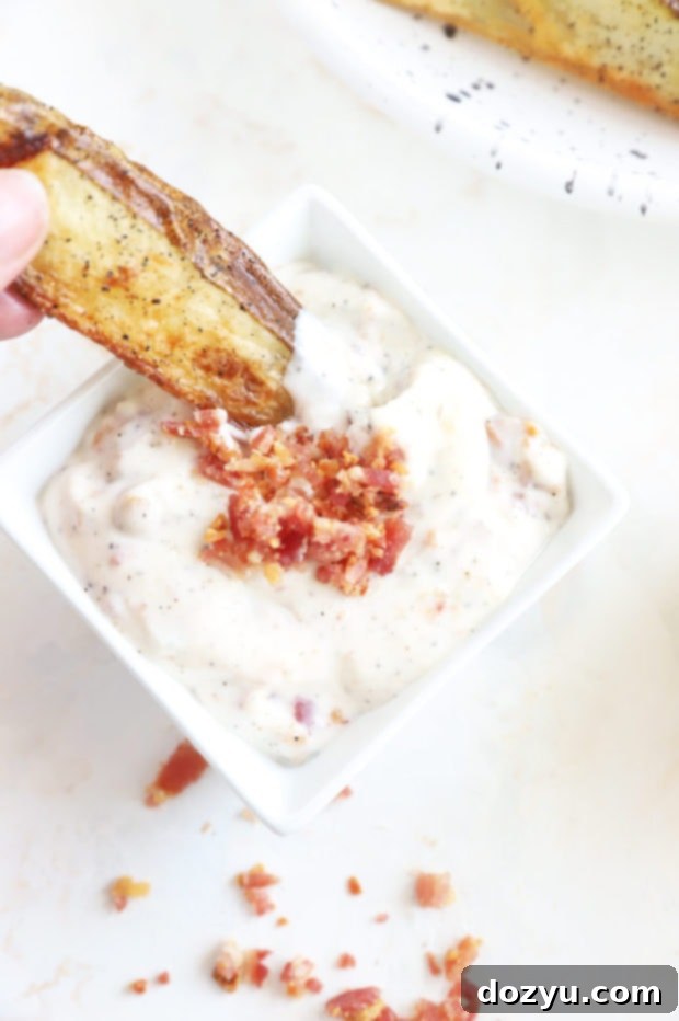 Smoky Bacon Aioli 6 A crispy French fry being dipped into a bowl of homemade bacon aioli.