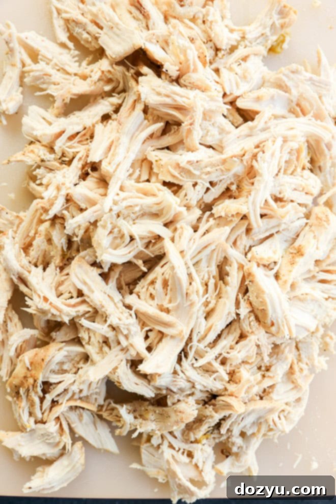 Dreamy Slow Cooker White Chicken Chili 6 Perfectly shredded slow-cooked chicken on a cutting board, ready to be returned to the chili.