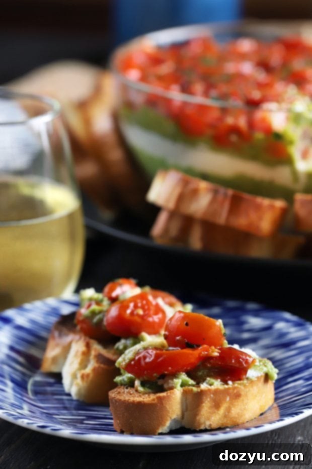 Avocado Ricotta Tomato Pesto Layer Dip with a serving spoon