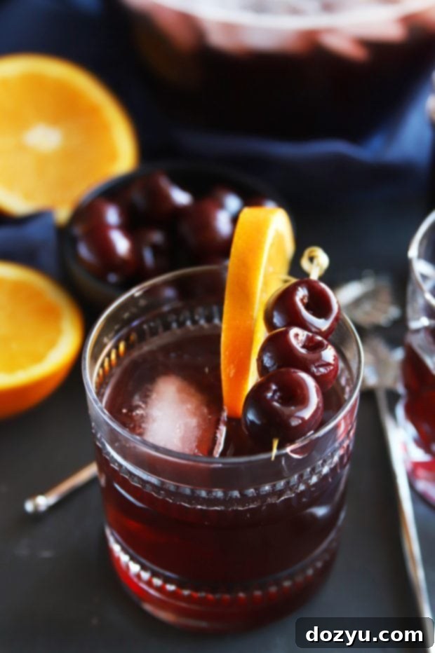 Close-up of Perfect Manhattan Punch with garnishes, highlighting the deep amber color and fresh fruit