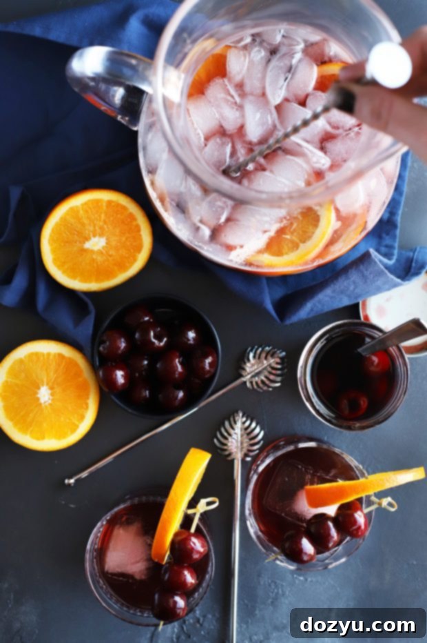 Close-up of a single glass of Perfect Manhattan Punch, garnished with a cherry and orange peel, ready to be enjoyed