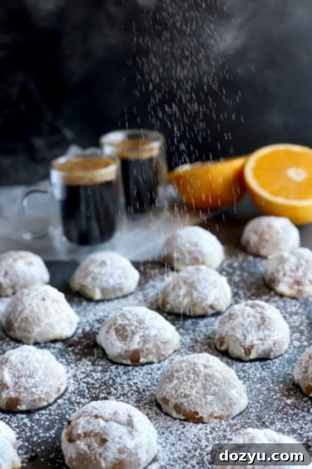 A hand reaching for a Mocha Orange Mexican Wedding Cookie on a white plate, emphasizing the irresistible appeal.
