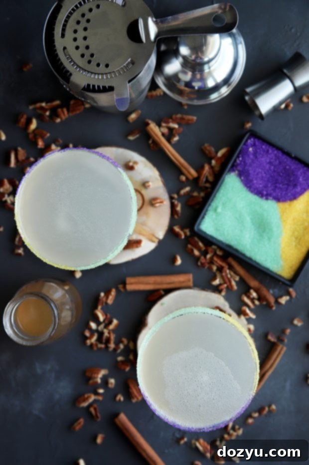 Ingredients for King Cake Daiquiri laid out, including cinnamon sticks, pecans, and citrus.