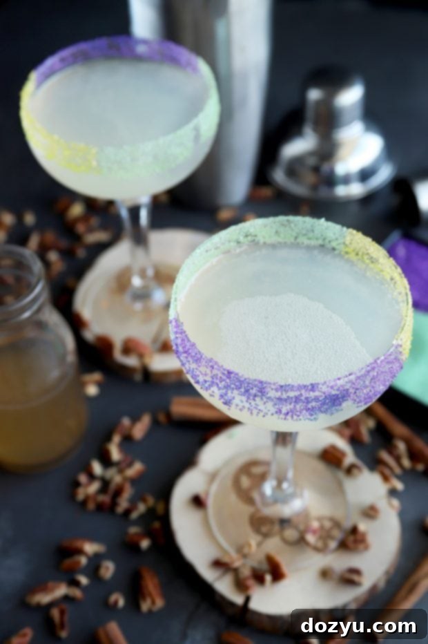 Two King Cake Daiquiris with festive sugar rims and Mardi Gras decorations, ready for a party.