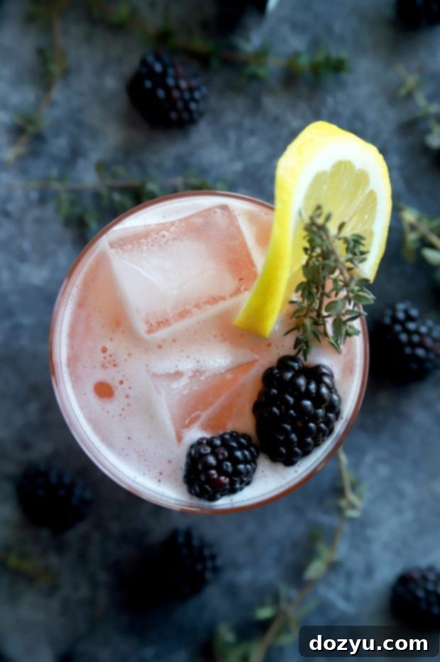 The Bramble & Thyme Irish Whiskey Sour 7 Two glasses of Blackberry Thyme Irish Whiskey Sour on a wooden surface.