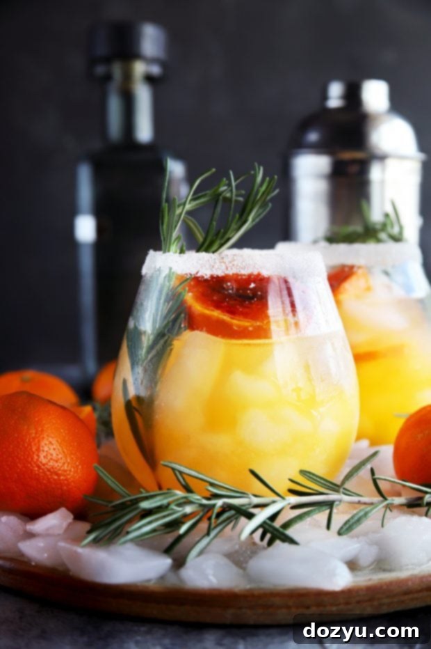 Close-up of Clementine Mezcal Margarita with ice and rosemary garnish