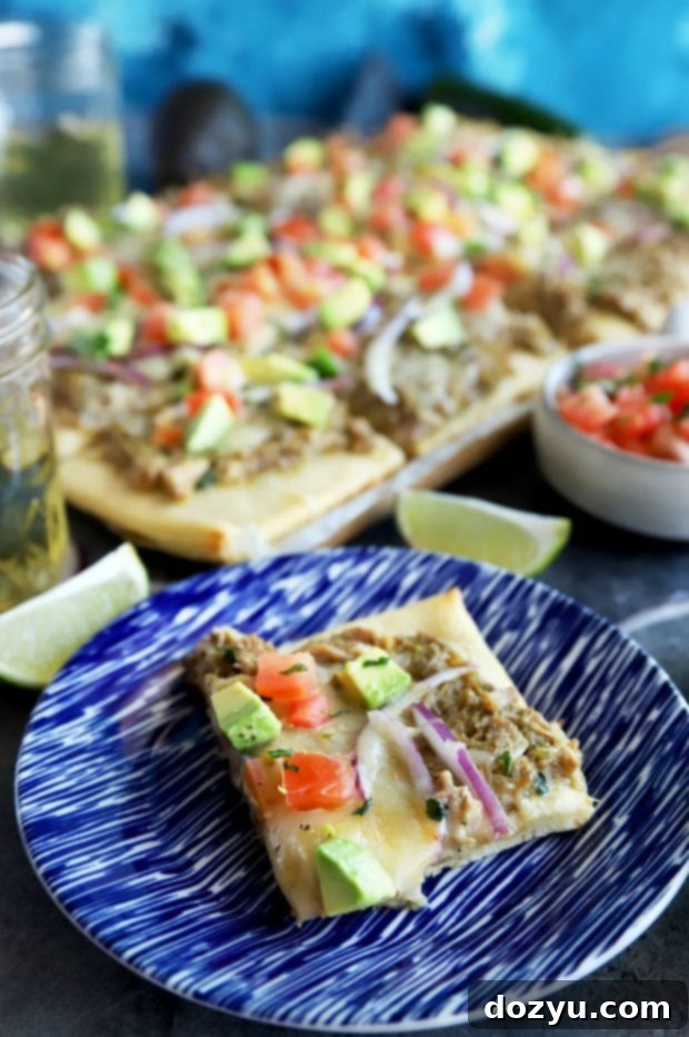 Close-up of Avocado Pulled Pork Flatbread with Grilled Tomatillo Salsa, showcasing vibrant toppings.