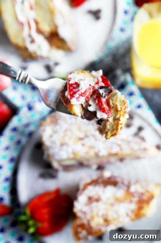 Fork lifting a piece of golden-brown stuffed French toast, showing the delicious filling