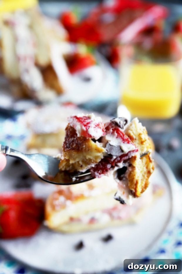 A fork taking a bite of a delicious breakfast with strawberries and chocolate, highlighting the rich filling