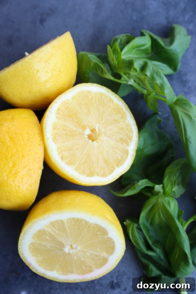 Close-up image of fresh lemon halves and vibrant basil leaves, highlighting the key ingredients for the cooler cocktail.