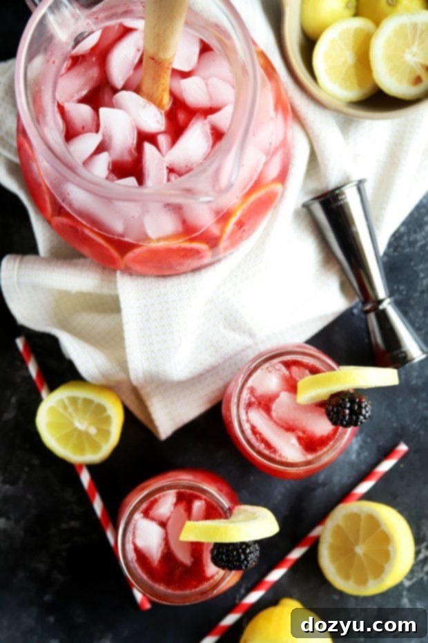 Big batch summer cocktail in a large glass pitcher for serving a crowd, featuring blackberry vodka lemonade