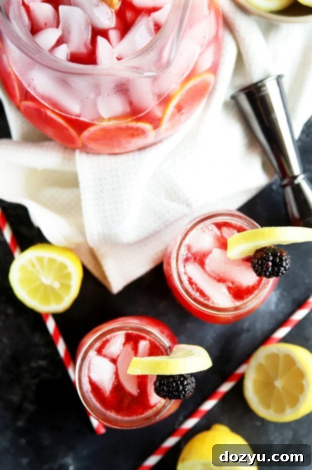 Sparkling Blackberry Vodka Lemonade in a glass with ice, fresh berries, and a lemon slice garnish