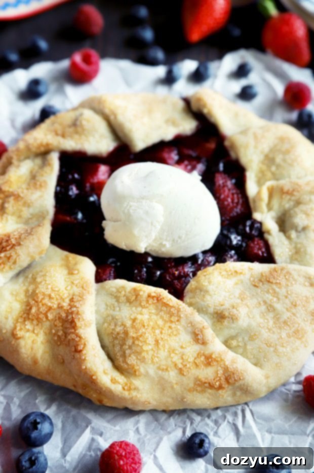 A close-up of a raspberry, blueberry, and strawberry galette before baking, with the crust folded beautifully around the fruit.