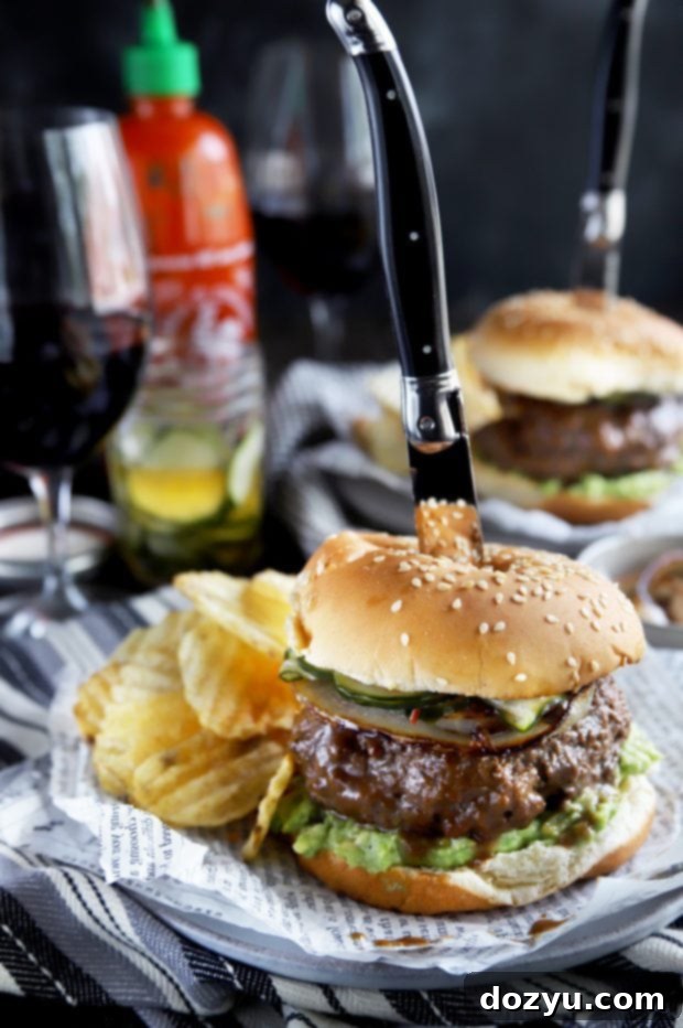 A grilled Asian-inspired burger, sliced in half to reveal its juicy interior and vibrant layers, accompanied by a knife.