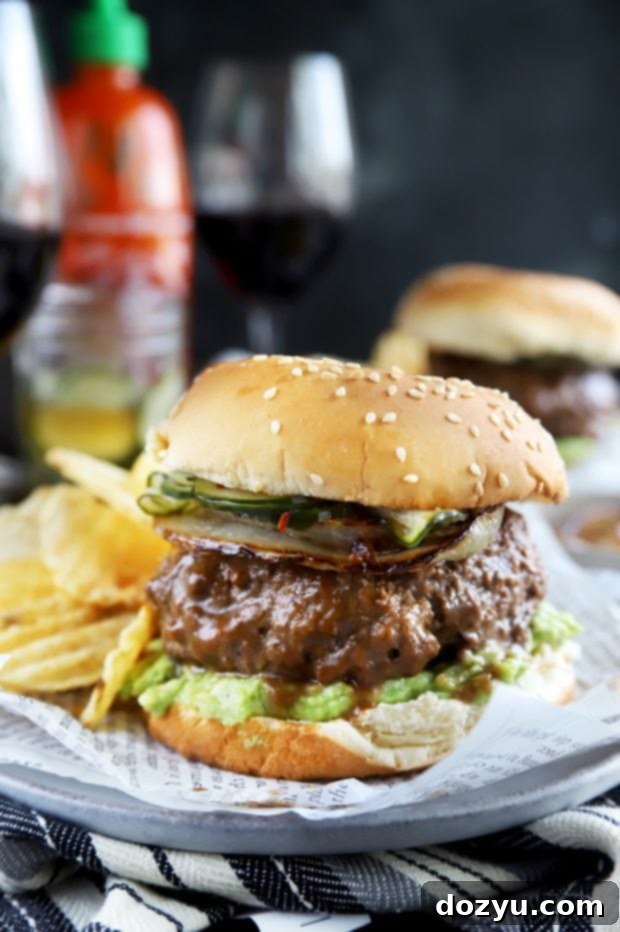 A towering gourmet Miso Glazed Sriracha Burger, stacked high with fresh ingredients, showcasing its impressive layers and mouth-watering appeal.