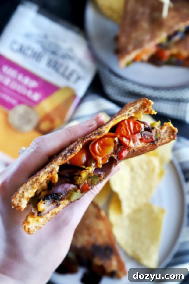 Holding half of a grilled cheese sandwich with grilled vegetables