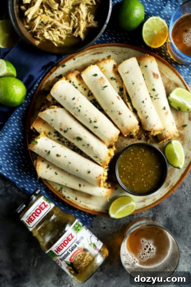 A festive party spread with baked taquitos, a bottle of HERDEZ salsa verde, and a glass of beer