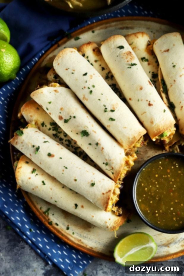 A close-up of a stack of creamy salsa verde chicken baked taquitos on a plate