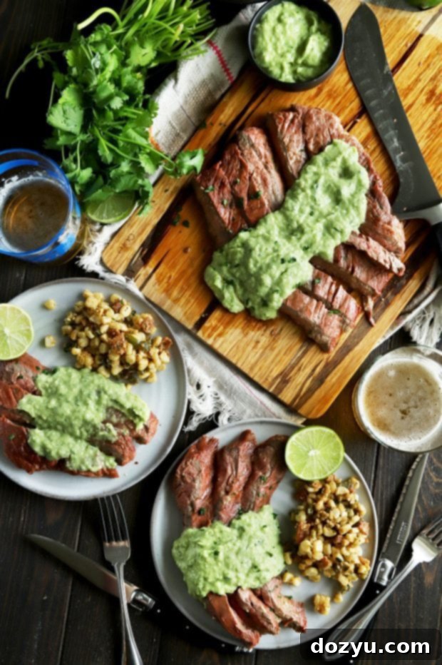 Overhead shot of grilled flank steak, corn salad, and creamy avocado salsa