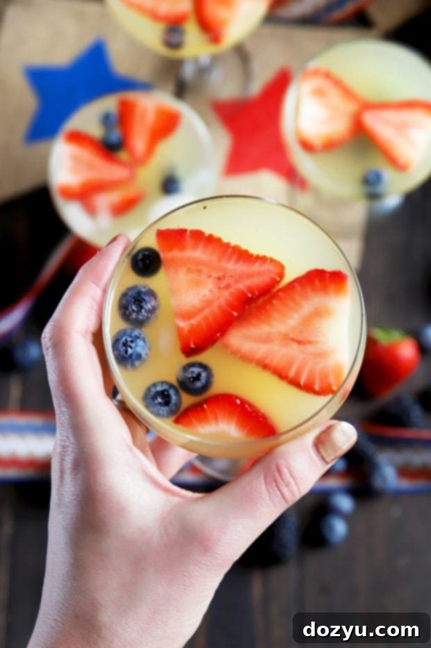 Patriotic Brunch Punch 8 Hand holding a patriotic cocktail recipe, showcasing fresh berries and bubbly